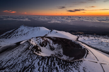 Volcanic landscape of Mount Etna with rugged lava fields, smoke rising from the crater, and...