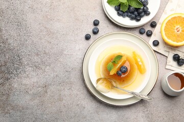 Tasty panna cotta with orange, blueberries and mint on light grey table, flat lay. Space for text
