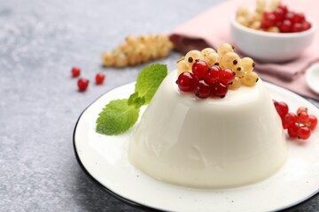 Tasty panna cotta with currants and mint on light grey table, closeup