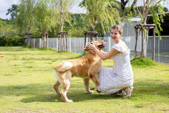 Caucasian woman hugging her cute energetic golden retriever dog in the outdoor park during summer for animal lover and pet sitter training concept