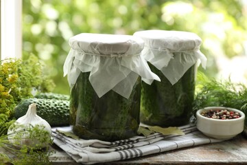 Making pickles. Fresh cucumbers in jars and spices on wooden table outdoors, closeup