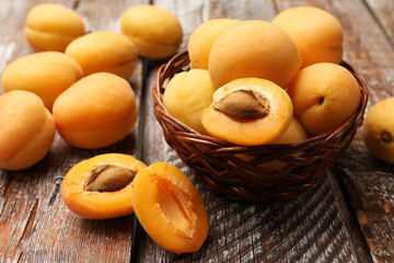 Fresh ripe apricots in wicker basket on wooden table, closeup