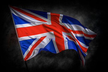 The Union Jack flag of the United Kingdom waves proudly against a dark textured background,...
