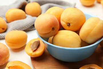 Fresh ripe apricots in bowl on white table, closeup