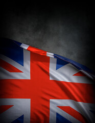 The Union Jack flag of the United Kingdom waves proudly against a dark textured background,...
