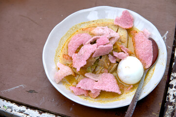 Authentic Lontong Padang, a traditional Indonesian dish featuring a rich stew, rice cakes, egg, and vibrant pink crackers.