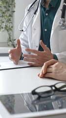 Doctor man wearing medical coat over green shirt, and stethoscope is gesturing with hands while...