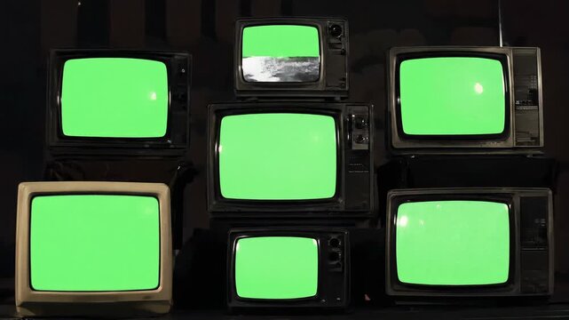 Multiple vintage televisions on black background, TVs of 80s, old retro televisions with bad signal reception, repeating pattern of many retro TVs with green screen chroma key and noise interference. 