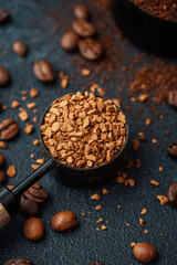 Instant coffee granules in scoop with coffee beans