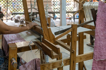 Hand weaving, making colorful silk fabric on wooden loom in traditional silk factory, Chiang Mai, Thailand. Handmade craftsmanship, artistry of textile production, sustainable vintage manufacture