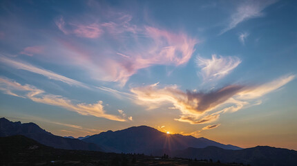 A breathtaking sunset paints the sky with hues of pink and orange, casting dramatic shadows over a mountain range.