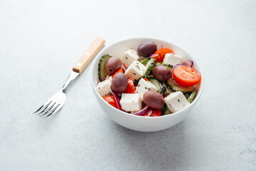 Greek salad with feta cheese olives cucumbers and tomatoes in white bowl
