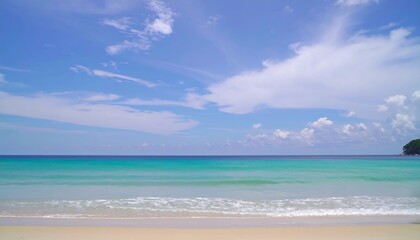 Fototapeta premium Serene beach scene with turquoise water lapping gently on the shore under a bright, partly cloudy sky