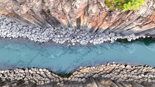 Aerial view of the stunning contrast between the geometric basalt columns and the flowing turquoise water, creating a mesmerizing natural artwork, Iceland.