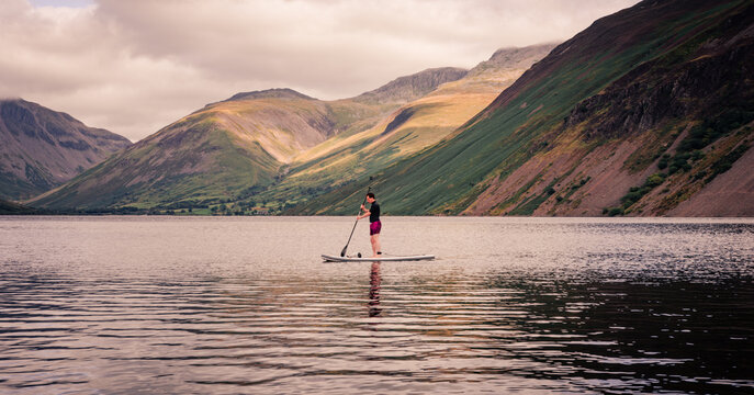paddle boarder on Wastwater lake with Scafell Pike and other mountains in the background  