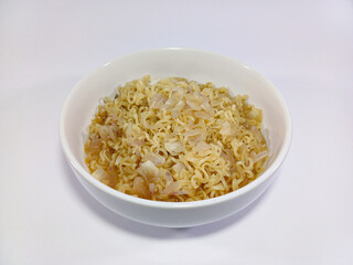 A bowl of instant ramen noodles with toppings, served in a white bowl against a white background....
