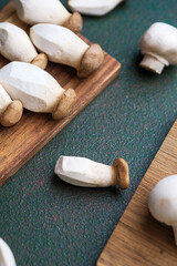 Assorted mushrooms on boards with dark green background for harvest variety or vegetarian cooking concept