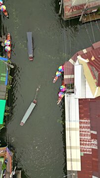 Aerial view of boats carrying colorful umbrellas along a river surrounded by buildings and greenery, Khet Phra Nakhon, Krung Thep Maha Nakhon, Thailand.