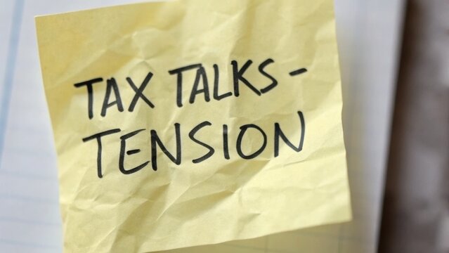 tax+rate+debate Sticky note with "Tax Talks - Tension" written on it, symbolizing stress related to taxes.