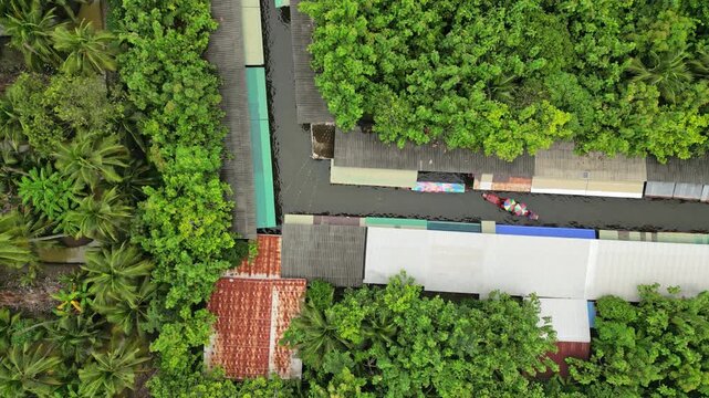 Aerial view of boats navigating along the river, with dense green trees contrasting with the buildings below, Khet Phra Nakhon, Krung Thep Maha Nakhon, Thailand.