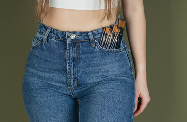 Female waist in jeans with paintbrushes in pocket for DIY project or home renovation concept