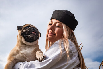 Young happy beautiful woman holding and hugging her beloved dog during a walk with harness and...