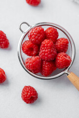 Raspberries in strainer on white background for cooking ingredient or minimal healthy snack concept
