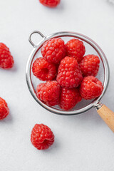 Raspberries in strainer on white background for cooking ingredient or minimal healthy snack concept