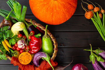 Fresh ripe vegetables in a basket on the black wooden background top view, autumn harvest of...