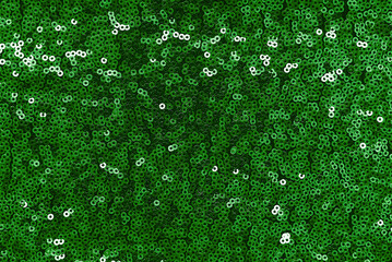 Texture of shiny fabric with sequins. Luxurious green background decorated with sequins
