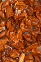 A close-up, full-frame shot of peeled almond skin, showcasing its wrinkled texture and brown color