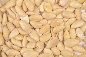 A detailed close-up, full-frame shot of a pile of raw, blanched almonds, showing their smooth texture and light color