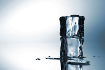 Two clear ice cubes stacked on a reflective surface with melting water droplets