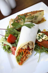 Chicken wrap with fresh vegetables and quiche on a white plate, healthy lunch
