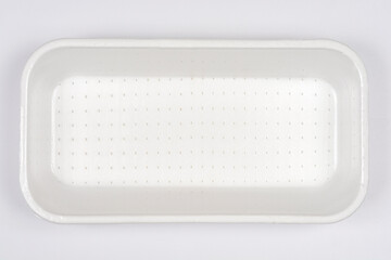 A clean, empty white styrofoam meat or fish tray, with a dotted texture on the bottom, positioned...