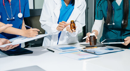 Healthcare professionals in uniform discussing lab reports, medication, and charts in a clinical office using tablets. Concept: teamwork, diagnosis, prescription.
