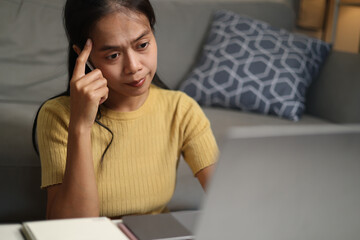 Selective focus shot, Young Asian woman sits on the floor taking online tutoring lessons on a...