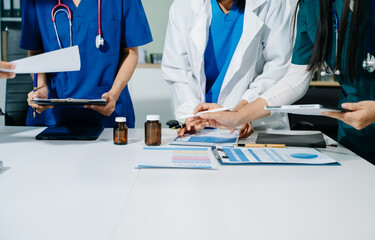 Healthcare professionals in uniform discussing lab reports, medication, and charts in a clinical...