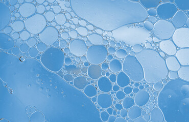 Close-up of blue oil bubbles in water creating a smooth abstract pattern with various round...