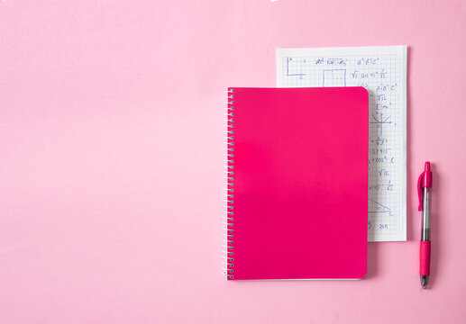Bright pink spiral notebook and pen on pastel pink background with visible math notes. A vibrant back-to-school scene that emphasizes color, learning, and student organization. - Powered by Adobe