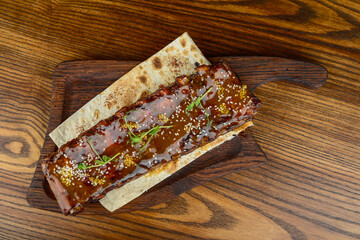 chopped fried ribs with sauce sprinkled with herbs on the background