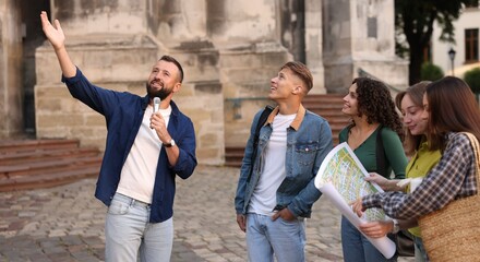 Guide with microphone and group of tourists on city street during excursion
