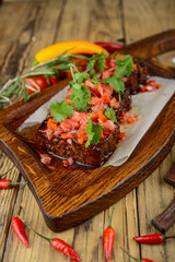 fried ribs with sauce sprinkled with tomatoes and herbs on the background