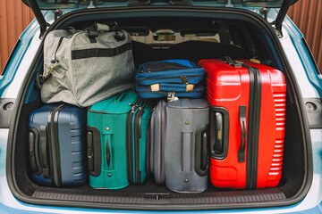 Car trunk is full of luggage. Open trunk of hybrid electric car with modern suitcases, ready for...