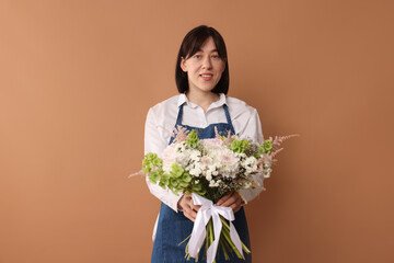 Florist with beautiful bouquet of flowers on dark beige background