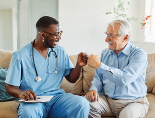 Doctor or nurse caregiver with senior man giving high five at home or nursing home