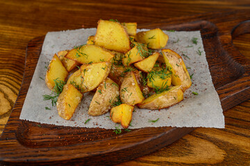 fried grilled potatoes in slices on parchment on a wooden board macro photo