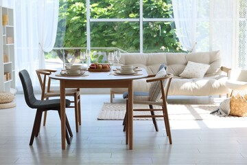Beautiful table setting, chairs and decor in dining room. Interior design
