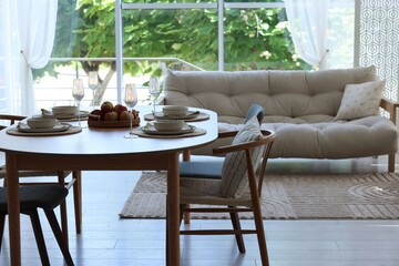 Beautiful table setting, chairs and decor in dining room. Interior design