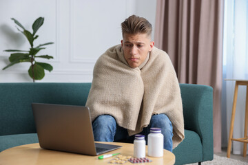 Sick man having online consultation with doctor via laptop at home